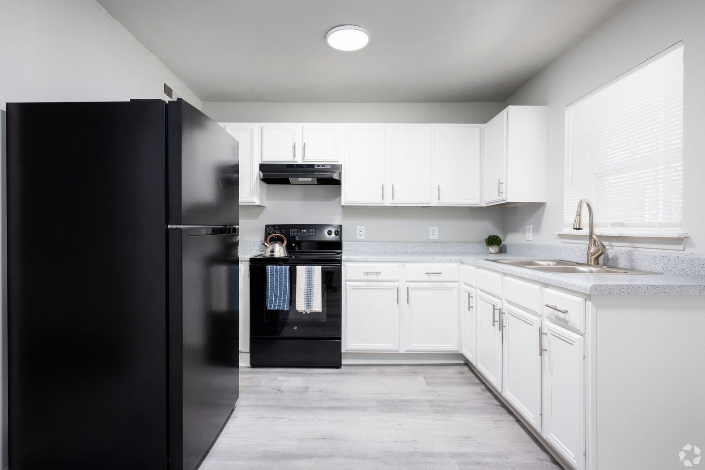 A kitchen with white cabinets , black appliances , and a black refrigerator.