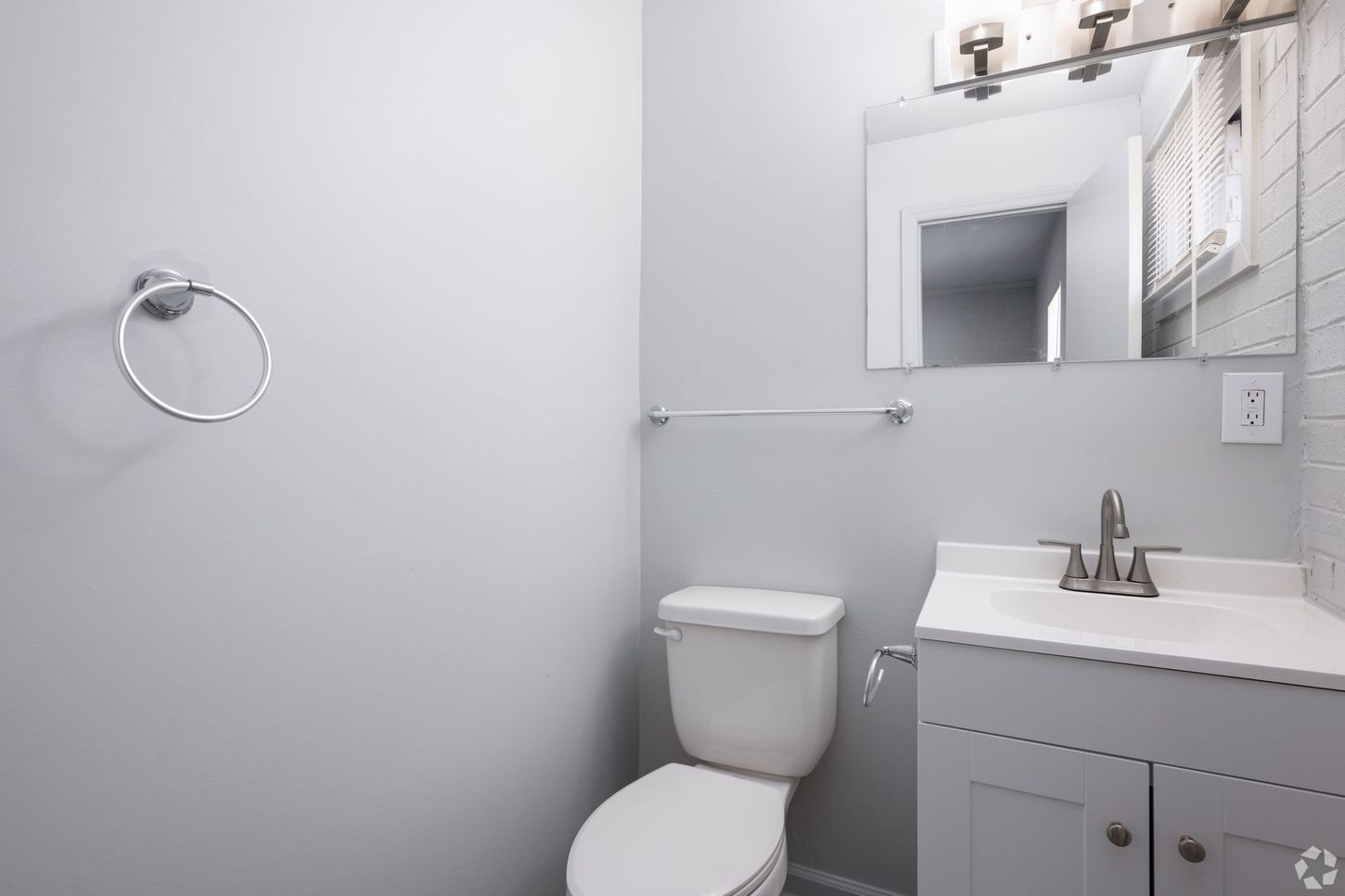 A bathroom with a toilet , sink and mirror.