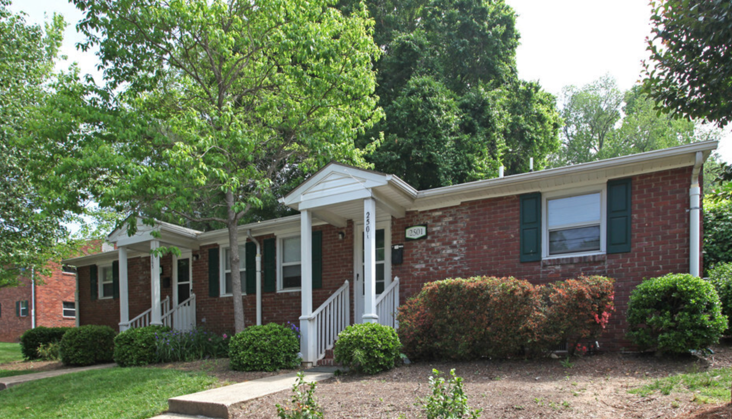 A brick house with a white porch and green shutters