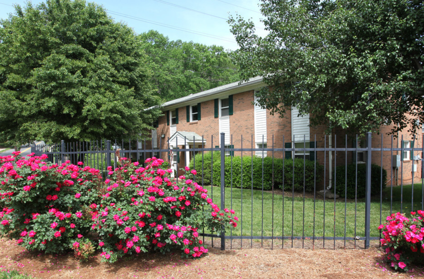 A brick house with a fence and flowers in front of it
