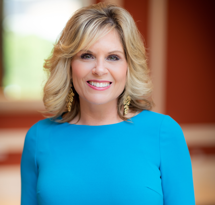 A woman in a blue dress is smiling for the camera.