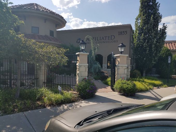 Two women are sitting in chairs talking to each other in front of a window.