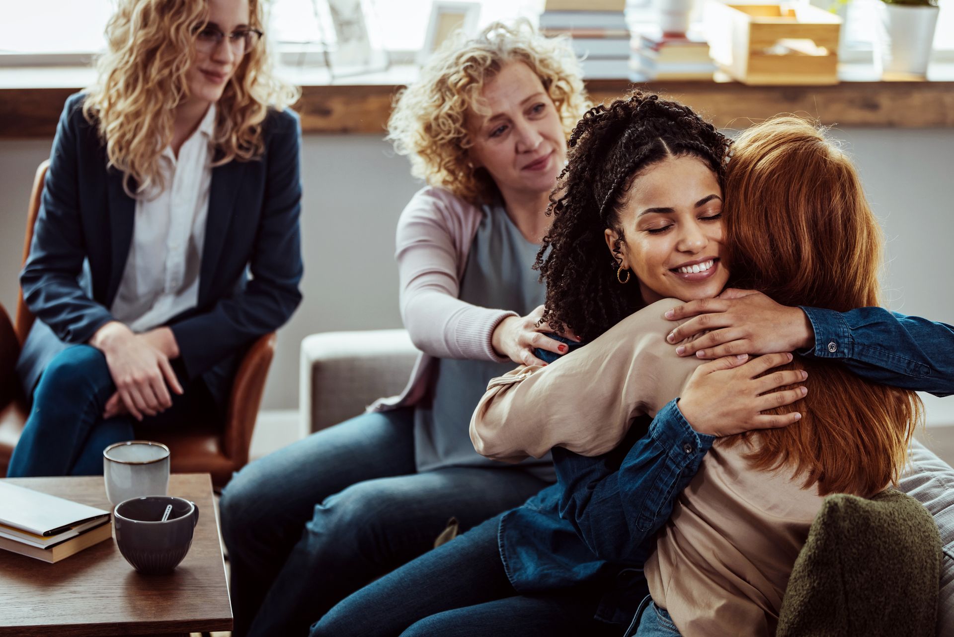 A group of women are hugging each other while sitting on a couch.