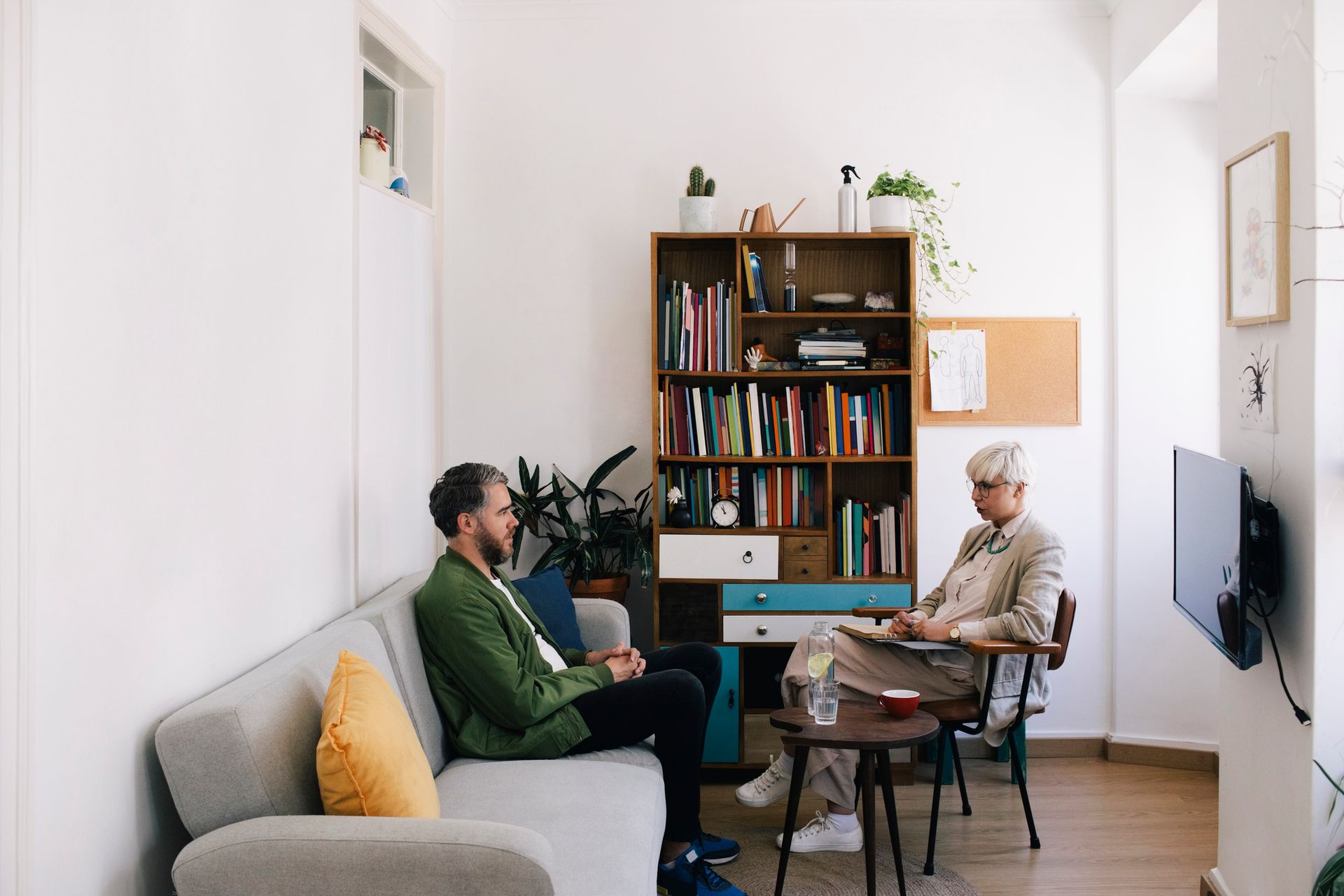 A female psychotherapist talking with a male patient sitting on a sofa at a therapy office A female psychotherapist talking with a male patient sitting on a sofa at a therapy office