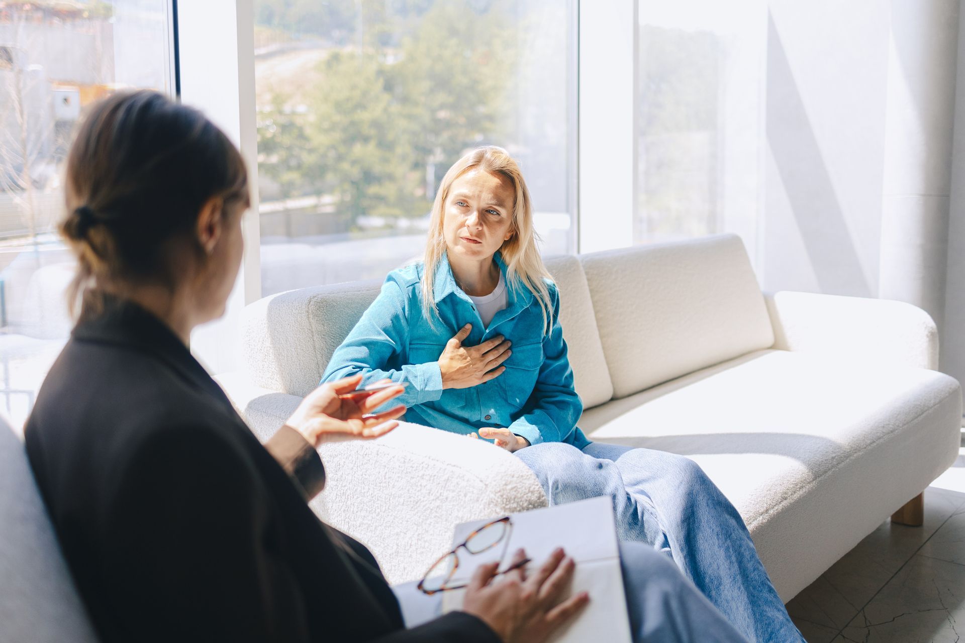 A woman is sitting on a couch talking to a therapist.