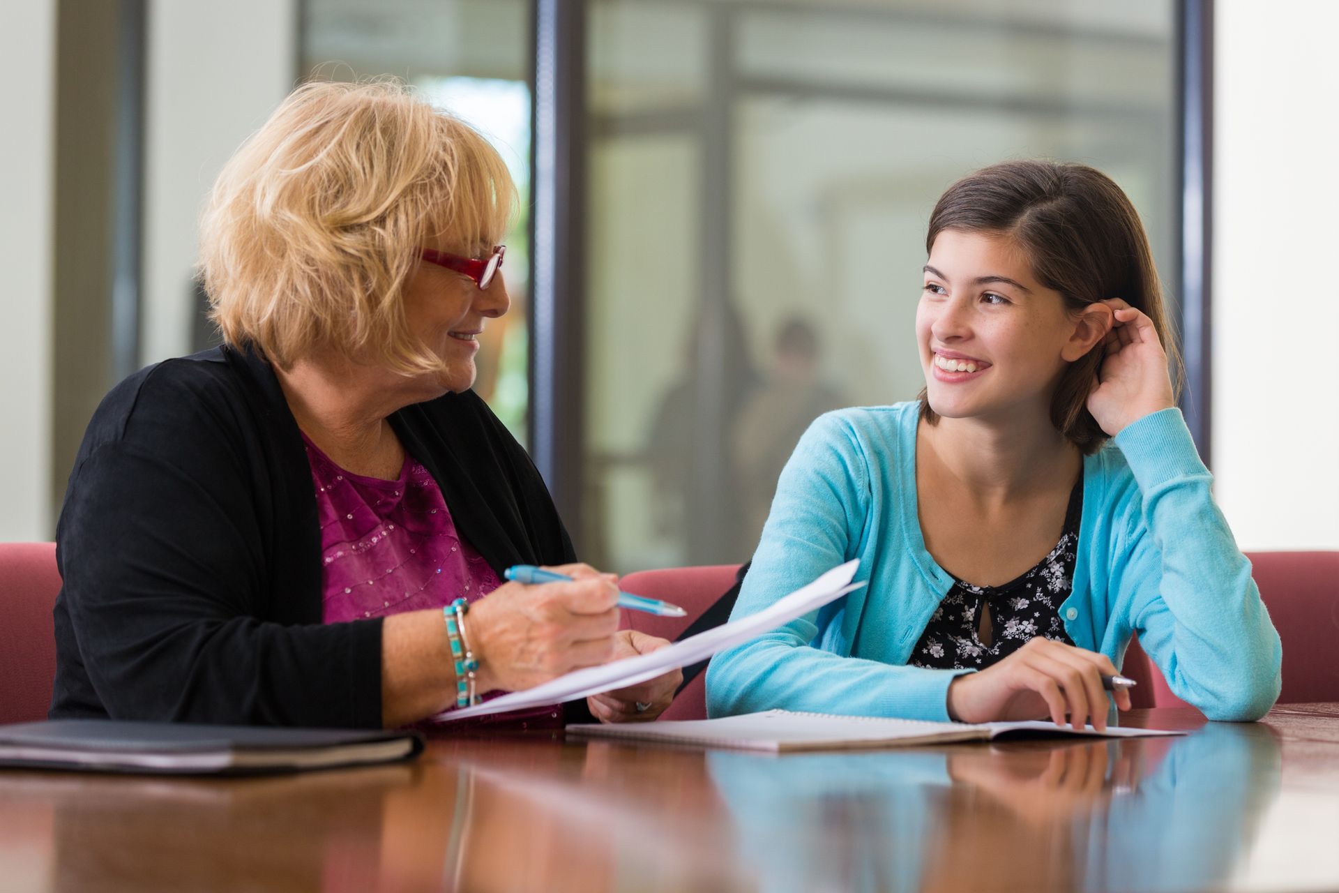 Two women are sitting at a table talking to each other.