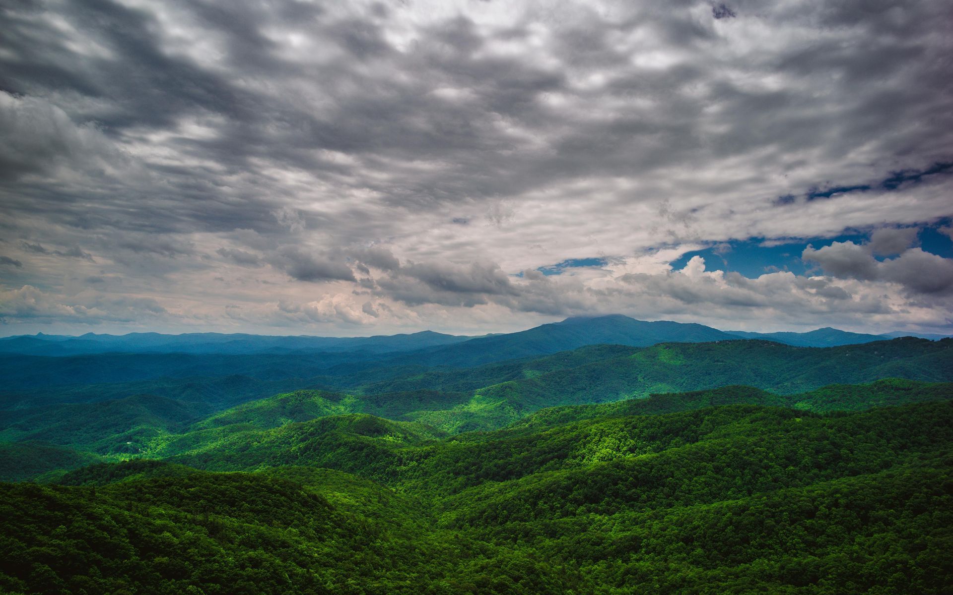 Green mountain range under a cloudy sky.