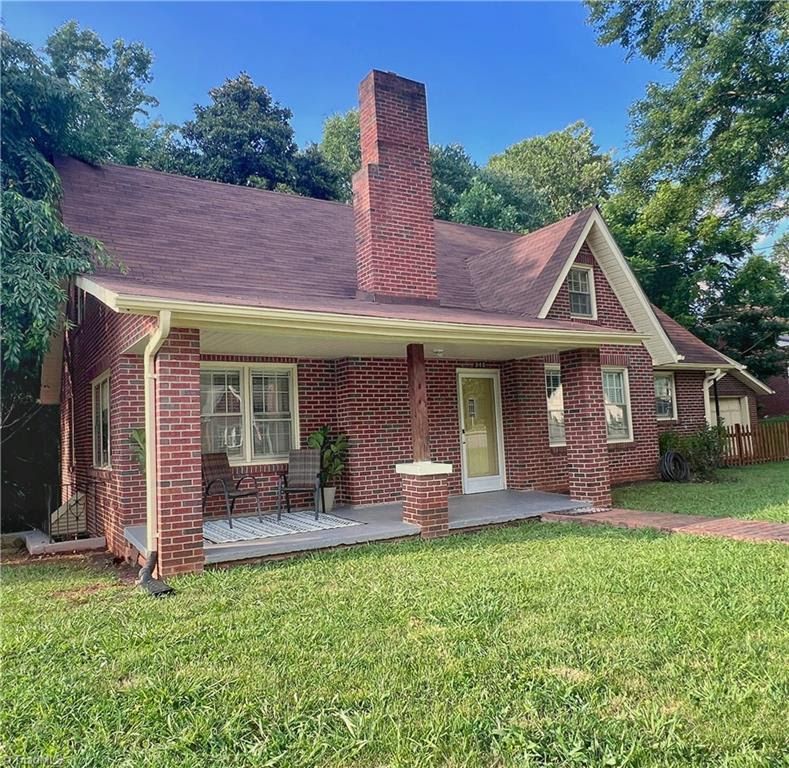 Brick house with porch, red roof, green lawn, and large brick chimney.Celeste Snow, Golden Key Realty Elkin NC