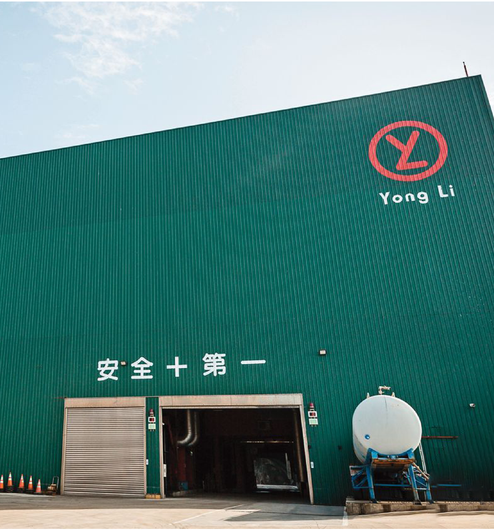 一座綠色的工業建築，有永利標誌、寬敞的入口，牆上還有「安全第一」的漢字。