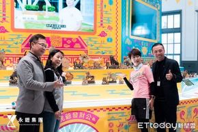 四個人站在一個色彩鮮豔、以黃色為主題的攤位前，攤位上陳列著一些小動物雕像。