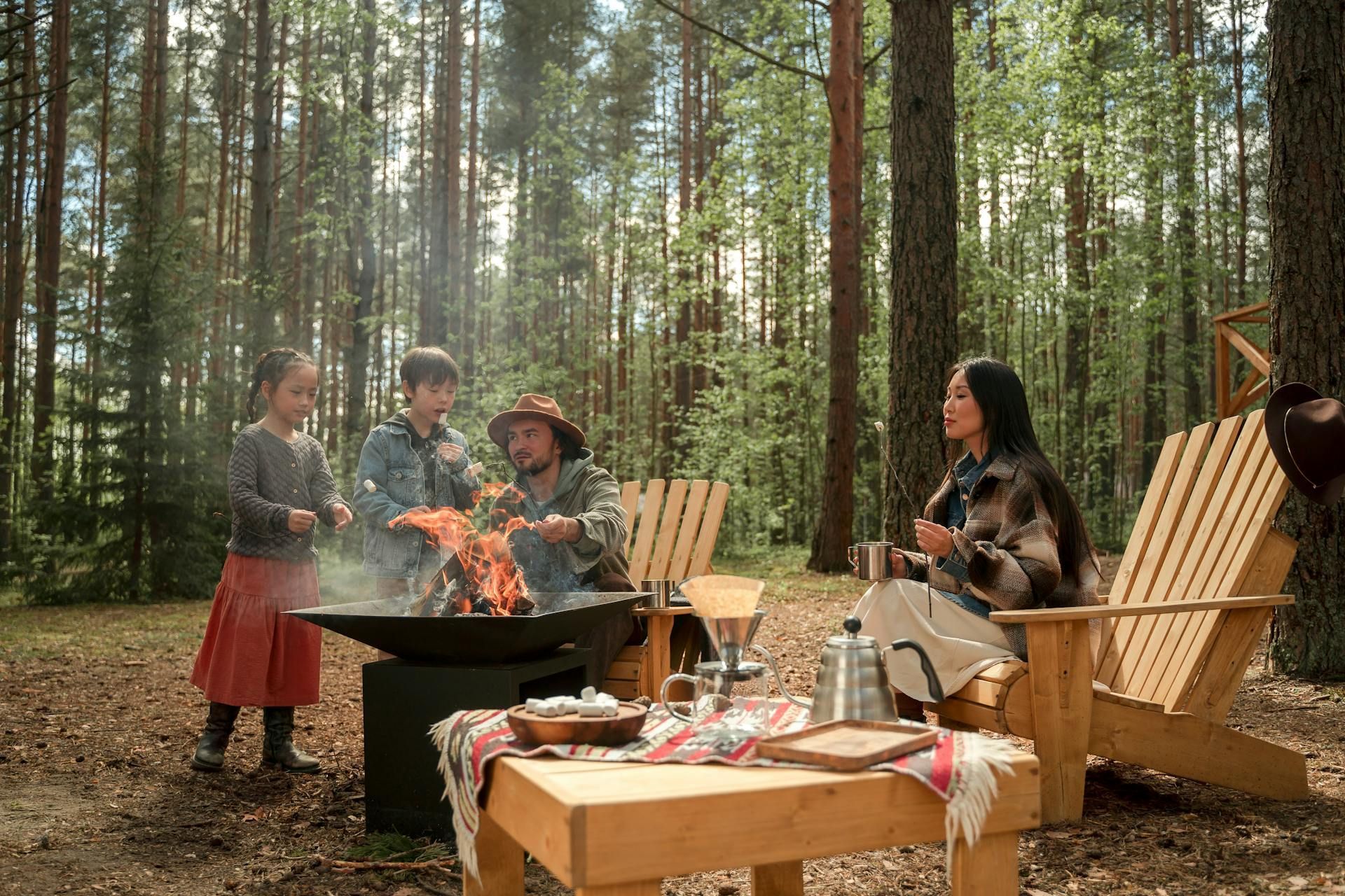 A group of people are sitting around a fire pit in the woods.