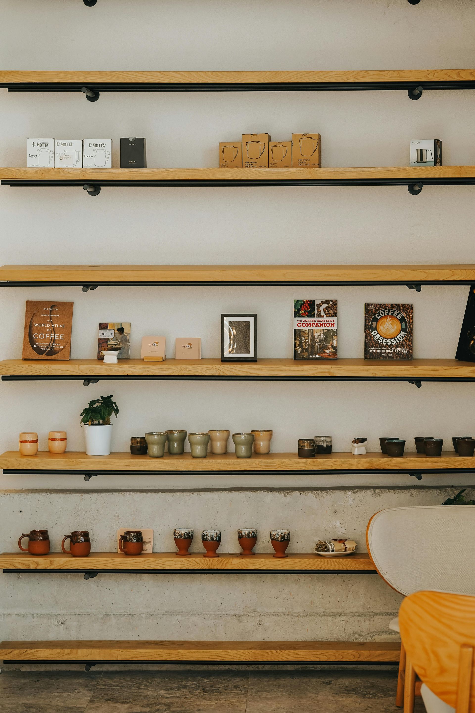 Wooden shelves display various ceramics, boxed goods, and decorative items against a neutral wall in a minimalist store.