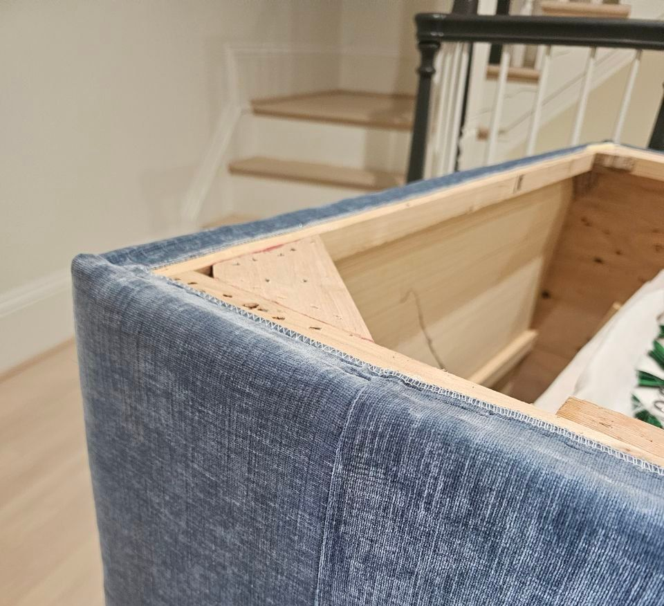 Blue upholstered furniture corner; wooden frame visible. Staircase in background.