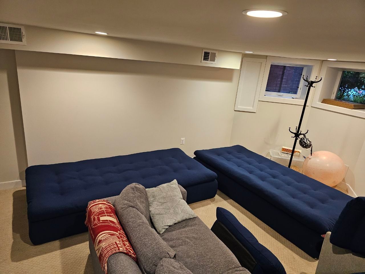 A basement with blue tufted seating and a neutral wall.