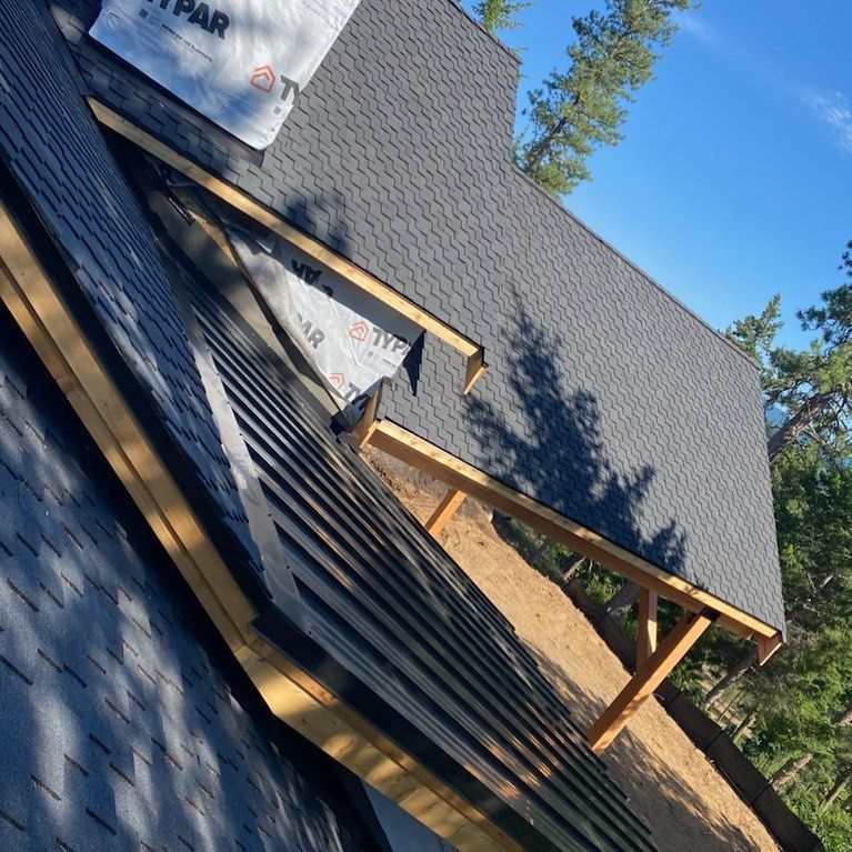 Roofing work in progress; dark shingles on sloped roof, wooden supports visible.