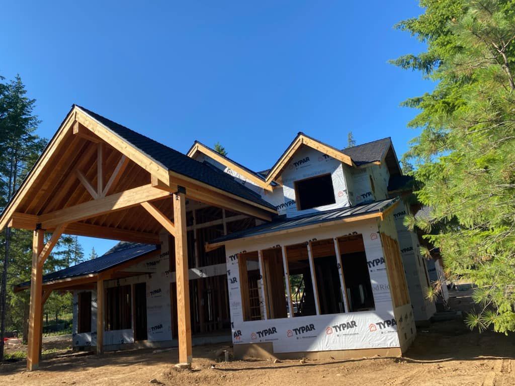House under construction with exposed wooden beams, blue sky.