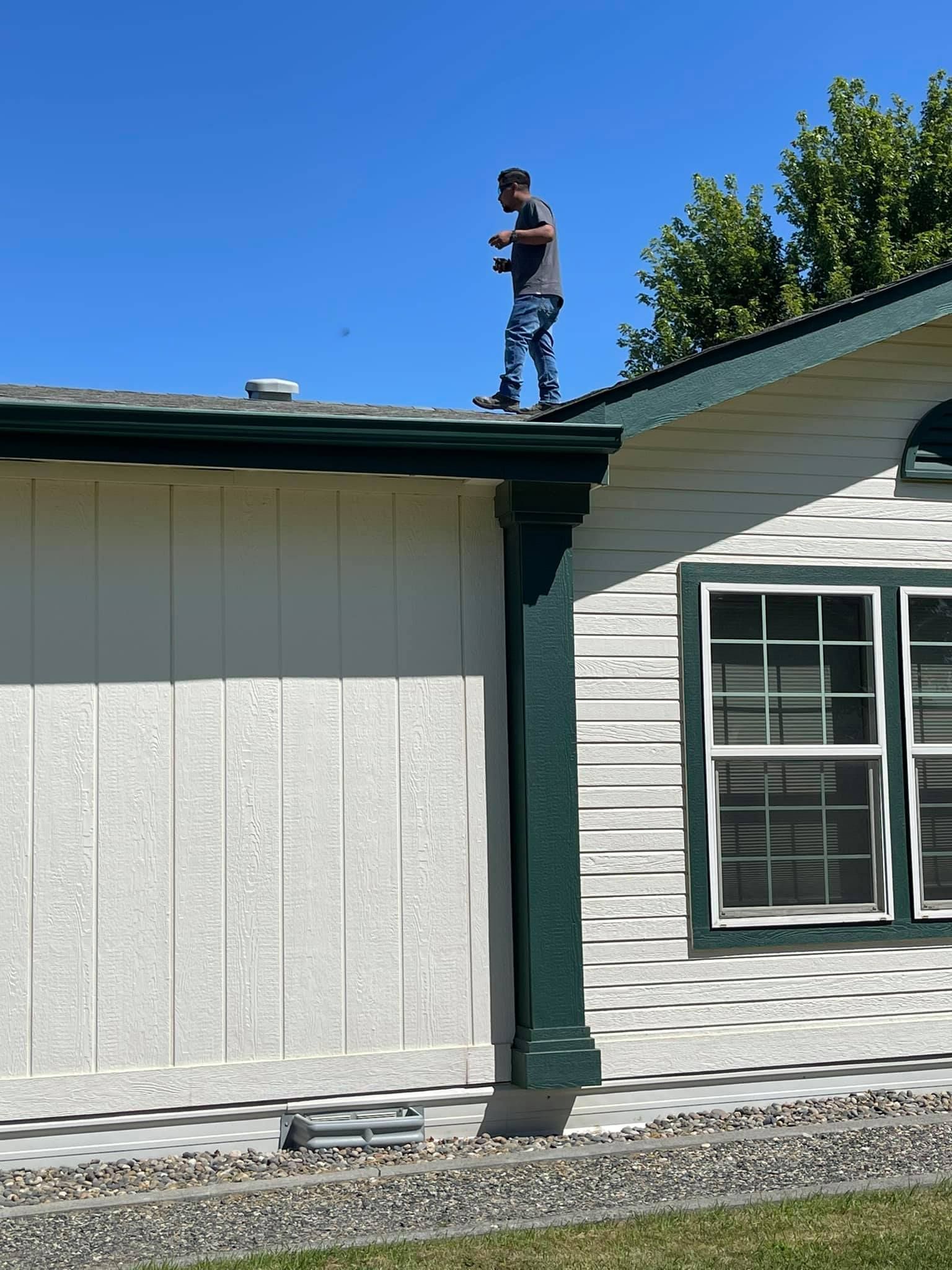 Person standing on a house roof holding an object under a blue sky.