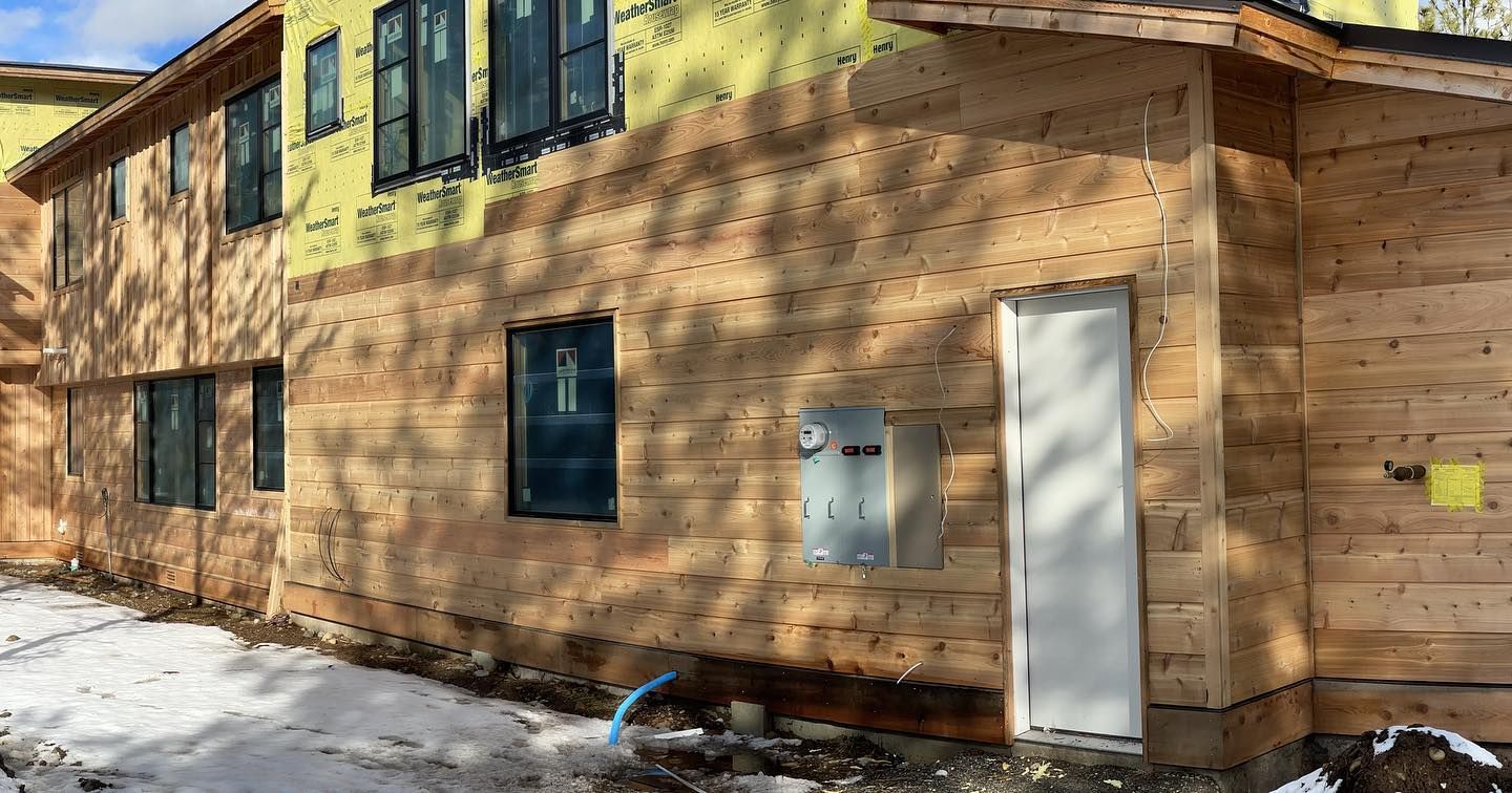 Building exterior under construction with exposed wood siding and a white door.