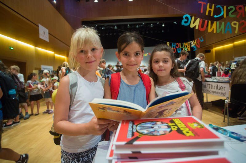 Drei junge Mädchen stehen nebeneinander und lesen Bücher.