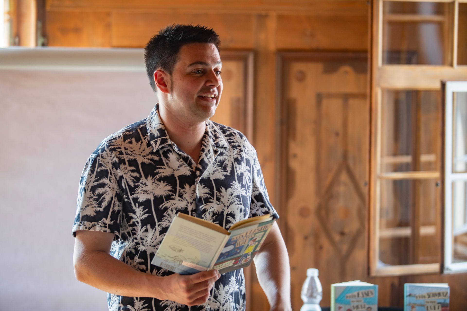 Ein Mann in einem Hawaiihemd liest in einem Zimmer ein Buch.