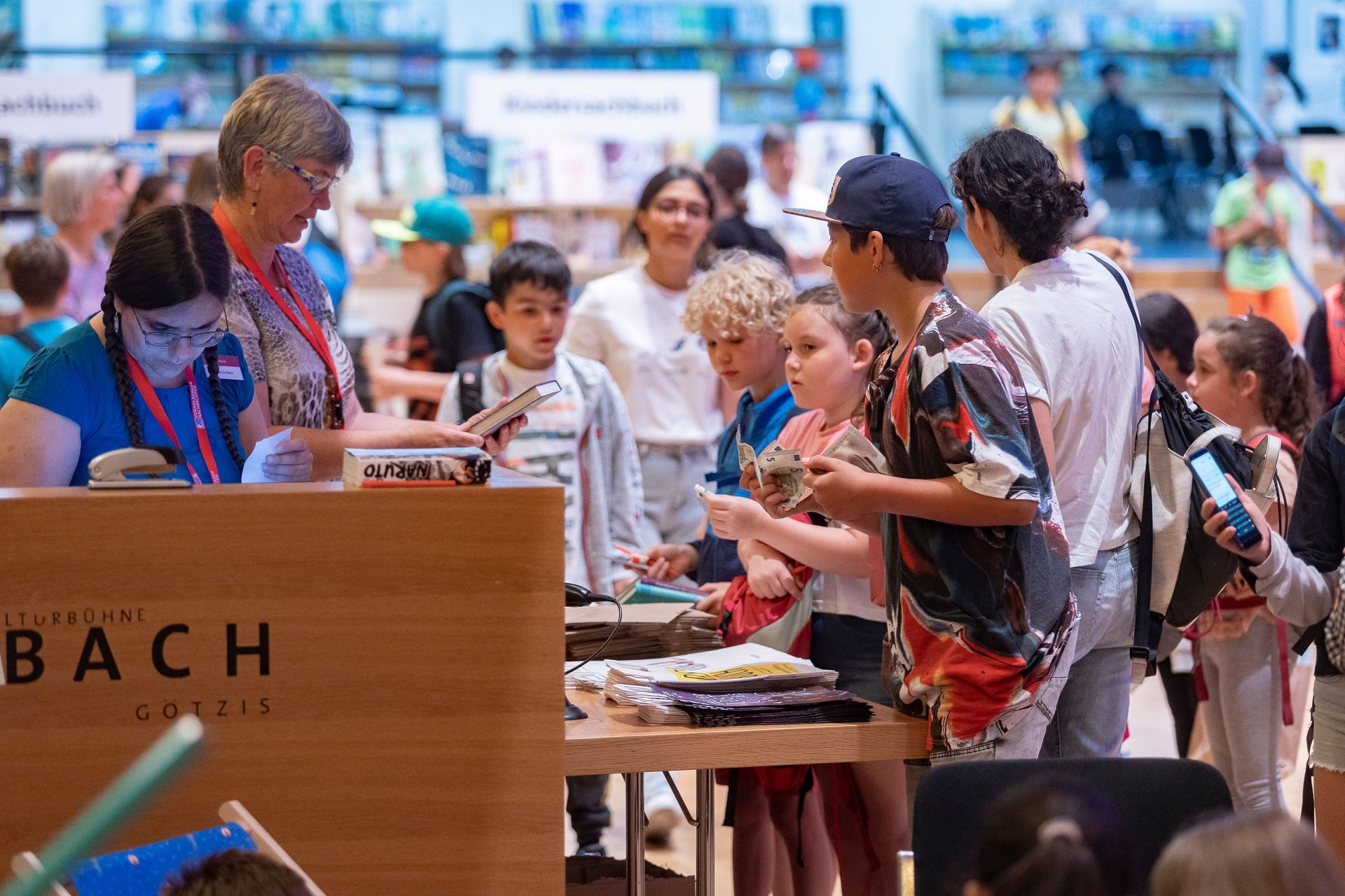 Eine Gruppe von Menschen steht in einer Bibliothek um einen Tisch herum.