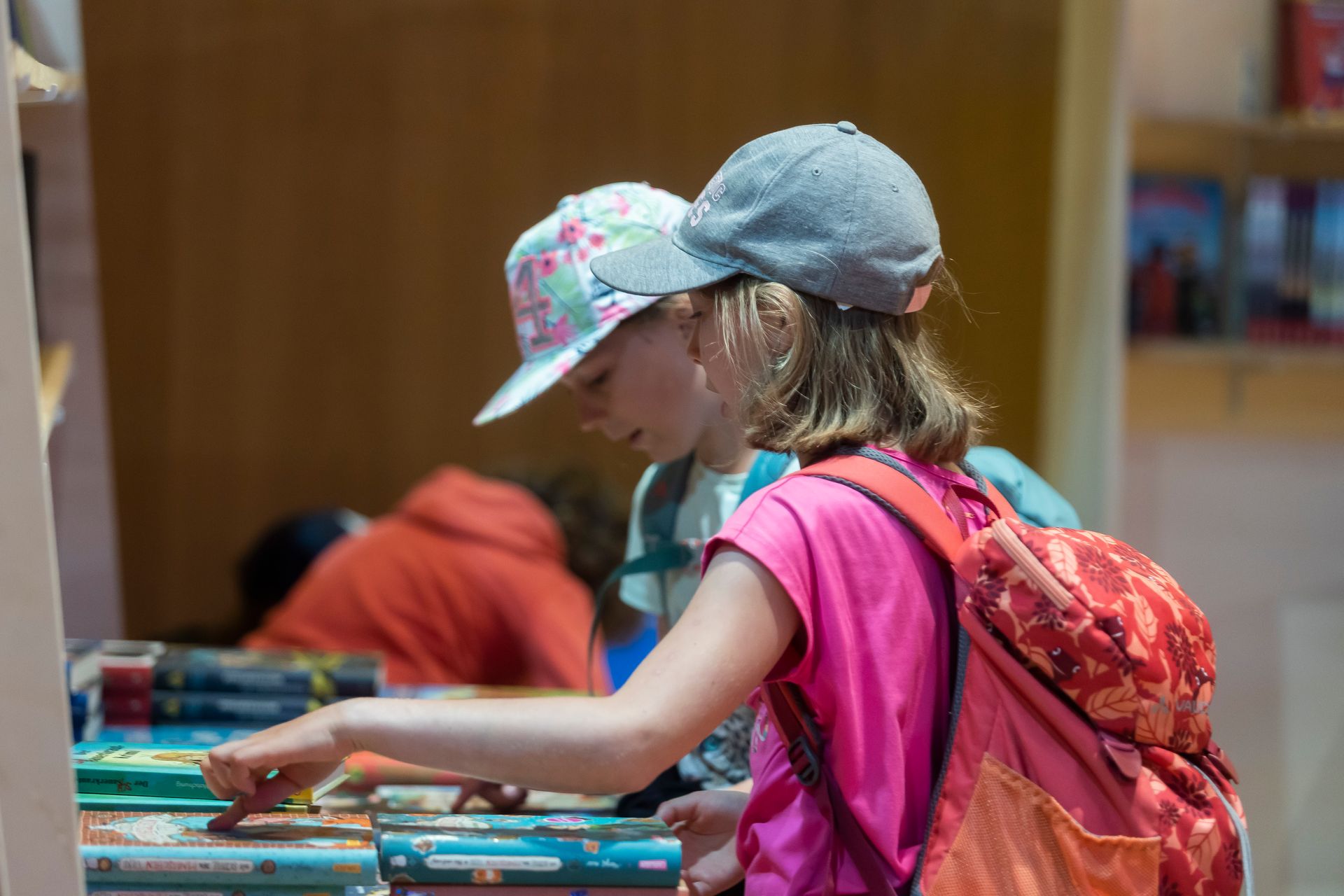 Ein Mädchen mit einem Rucksack sieht sich in einem Geschäft Bücher an.