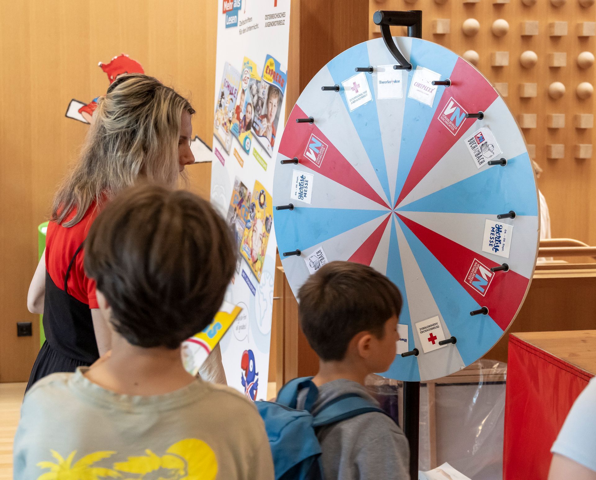 Eine Gruppe Kinder schaut sich ein buntes Spinnrad an.