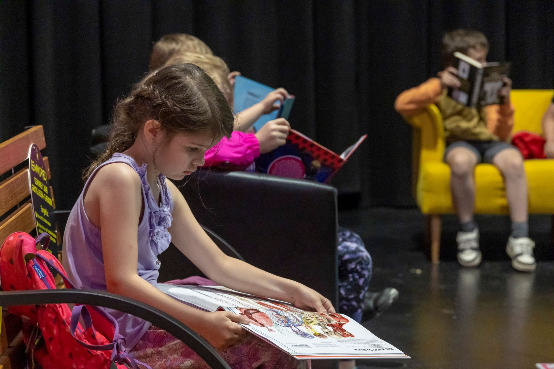 Eine Gruppe Kinder sitzt auf einer Bank und liest Bücher.