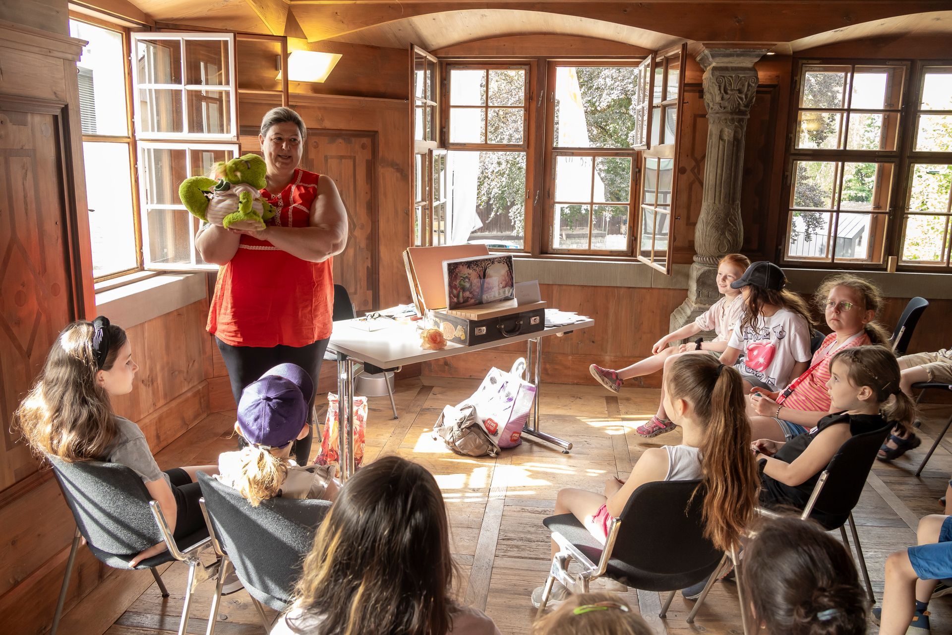 Eine Gruppe von Kindern sitzt in einem Raum im Kreis.