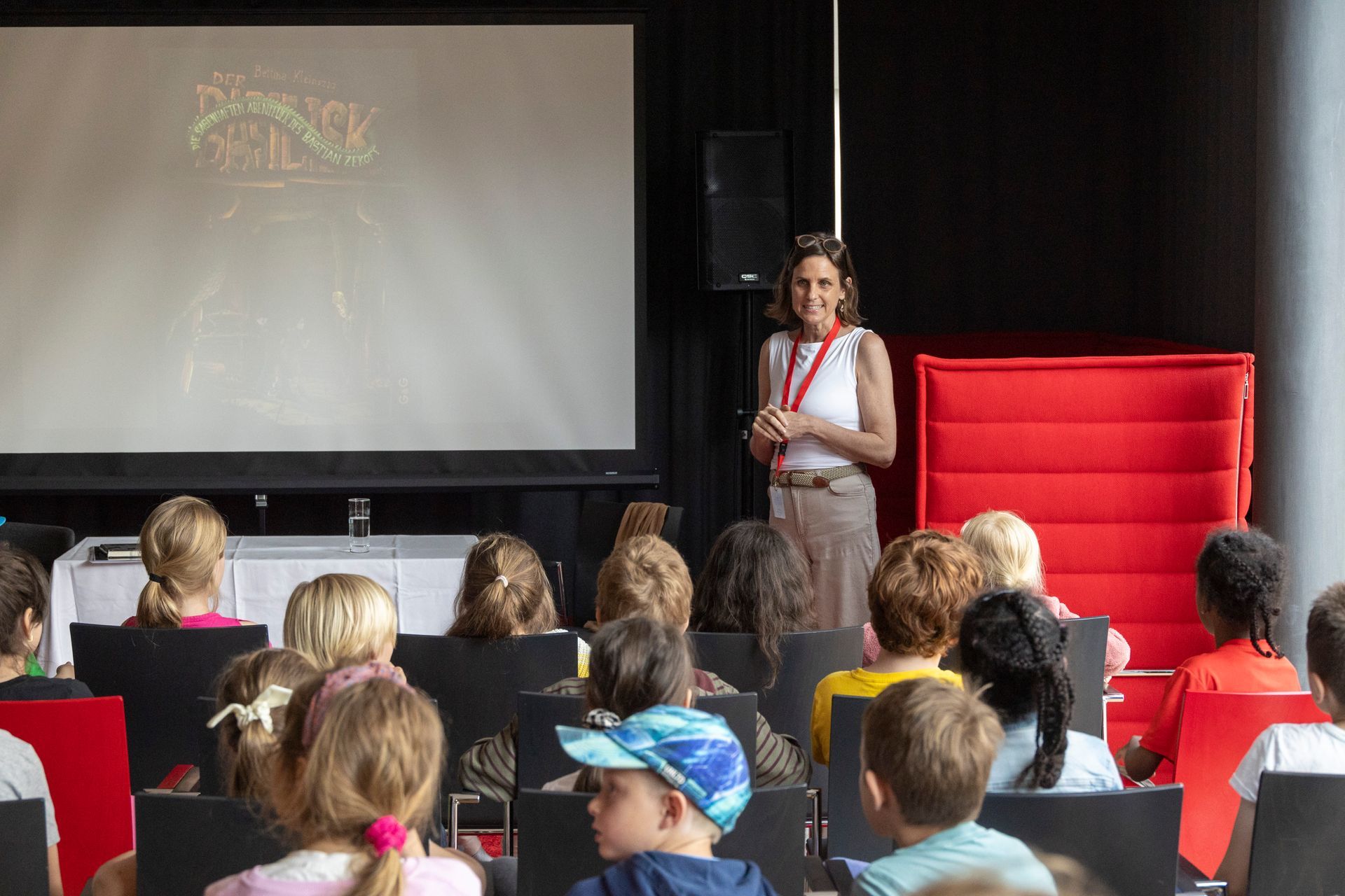 Eine Frau hält in einem Auditorium vor einer Gruppe von Kindern einen Vortrag.