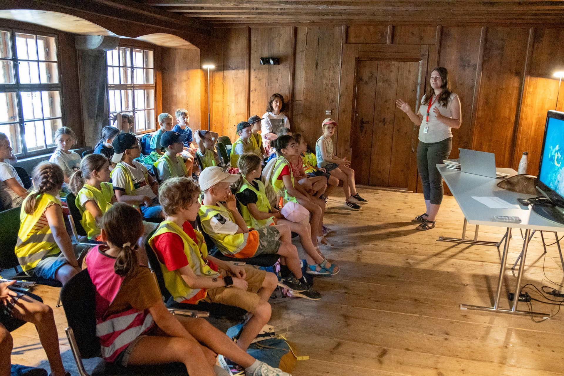 Eine Gruppe von Kindern sitzt in einem Raum und sieht sich eine Präsentation an.
