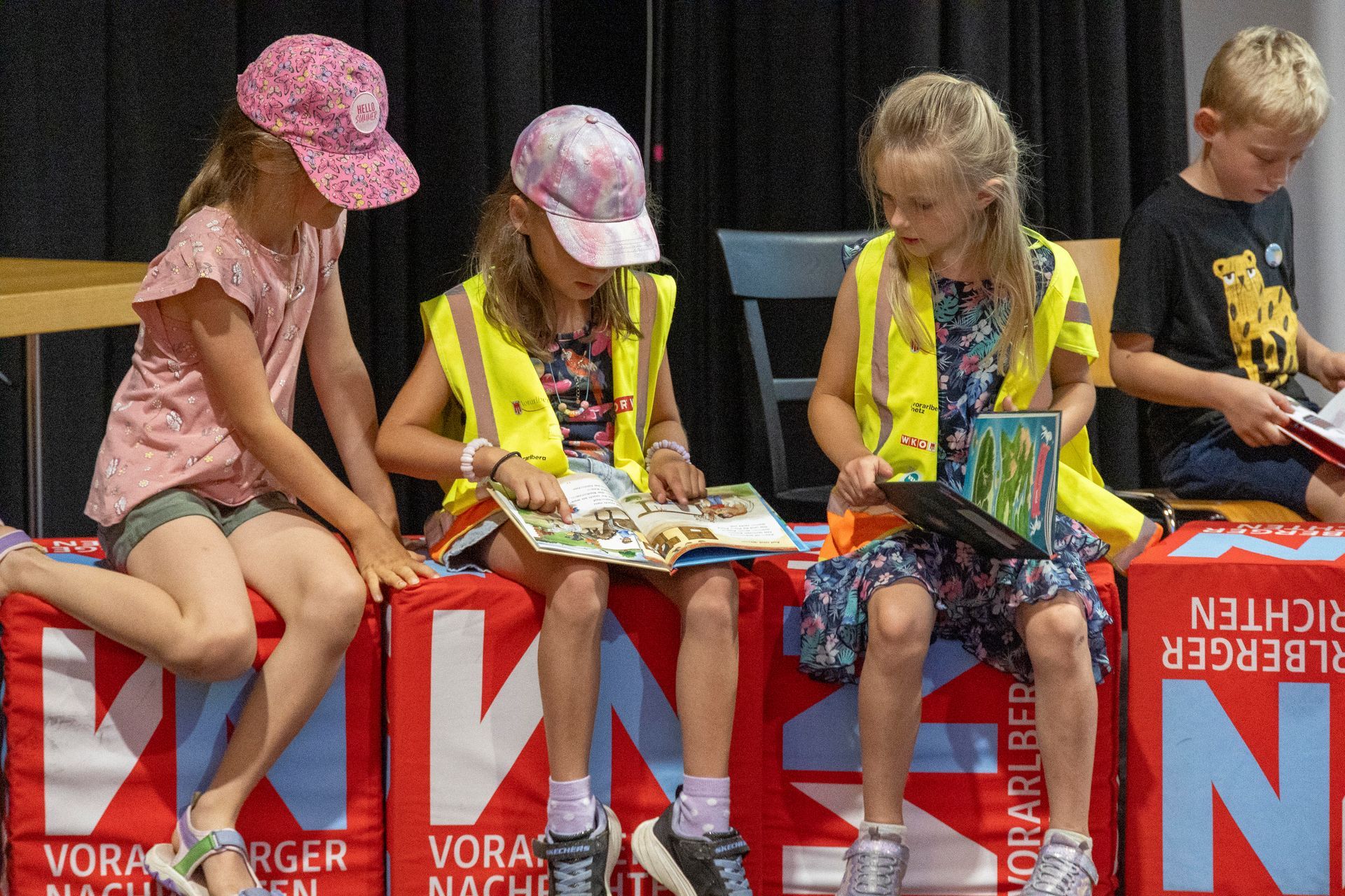 Eine Gruppe Kinder sitzt auf Kisten und liest Bücher.