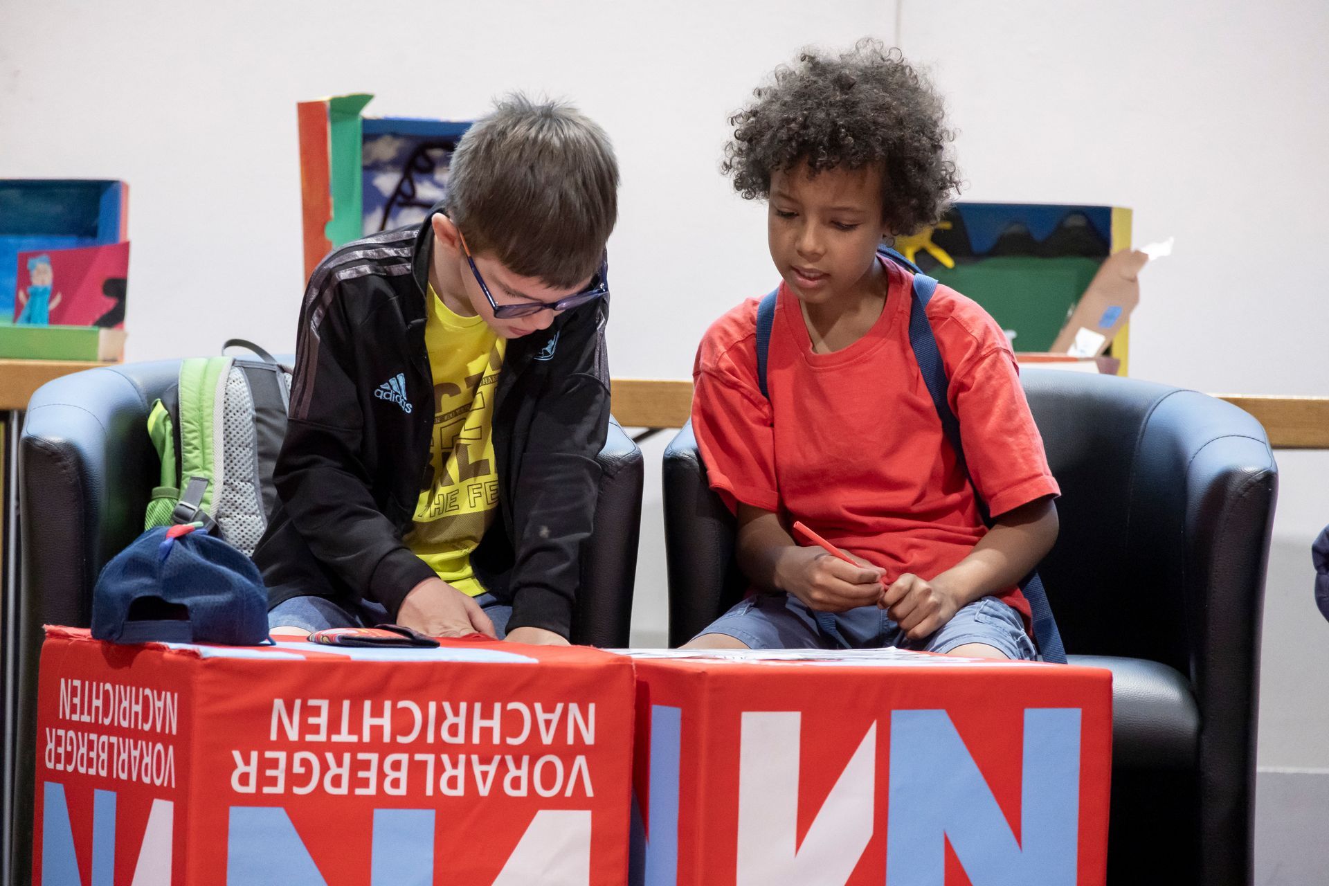 Zwei junge Jungen sitzen an einem Tisch mit einem Schild mit der Aufschrift n1