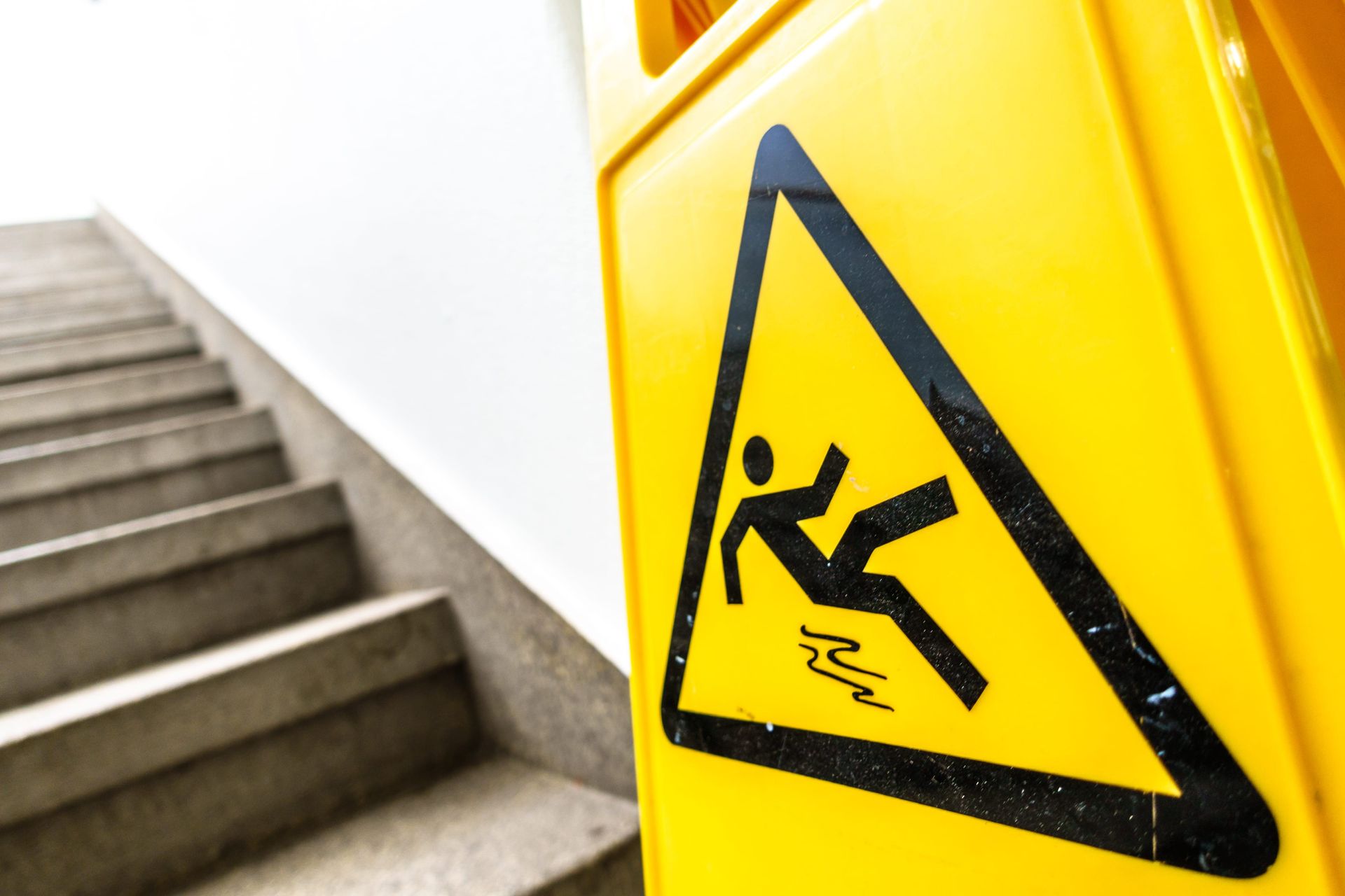 Yellow wet floor warning sign beside a stairwell with stairs in the background