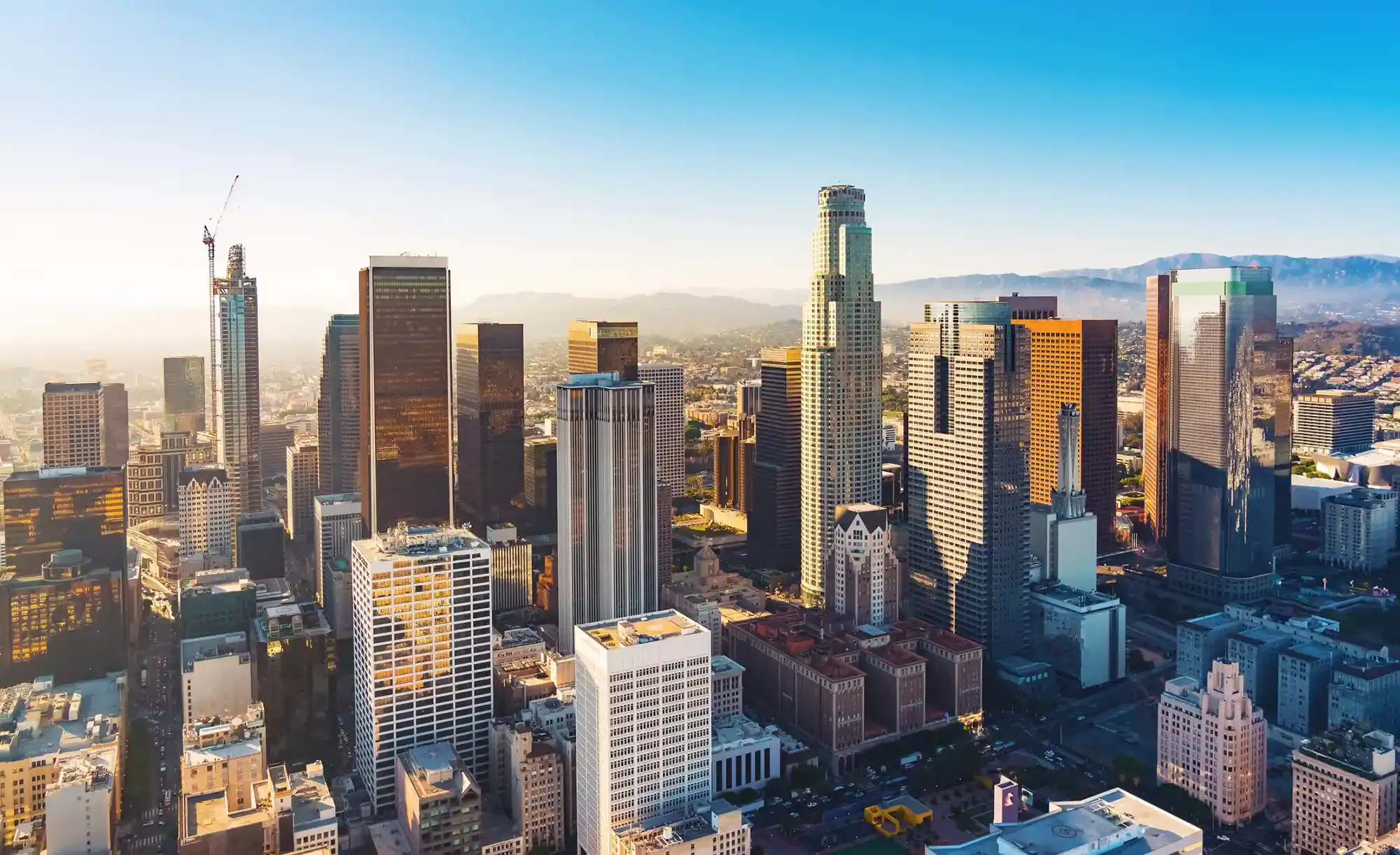 City skyline with skyscrapers under a clear blue sky, buildings reflecting sunlight.