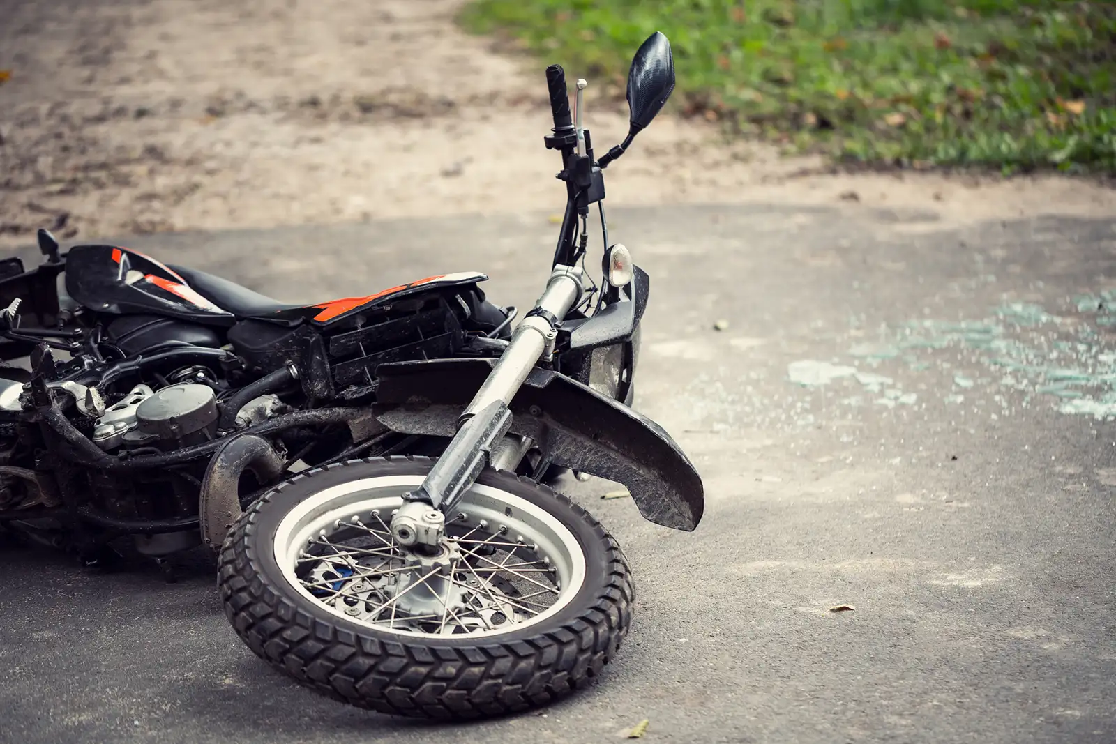 Motorcycle lying on its side on a paved road, possibly after an accident.
