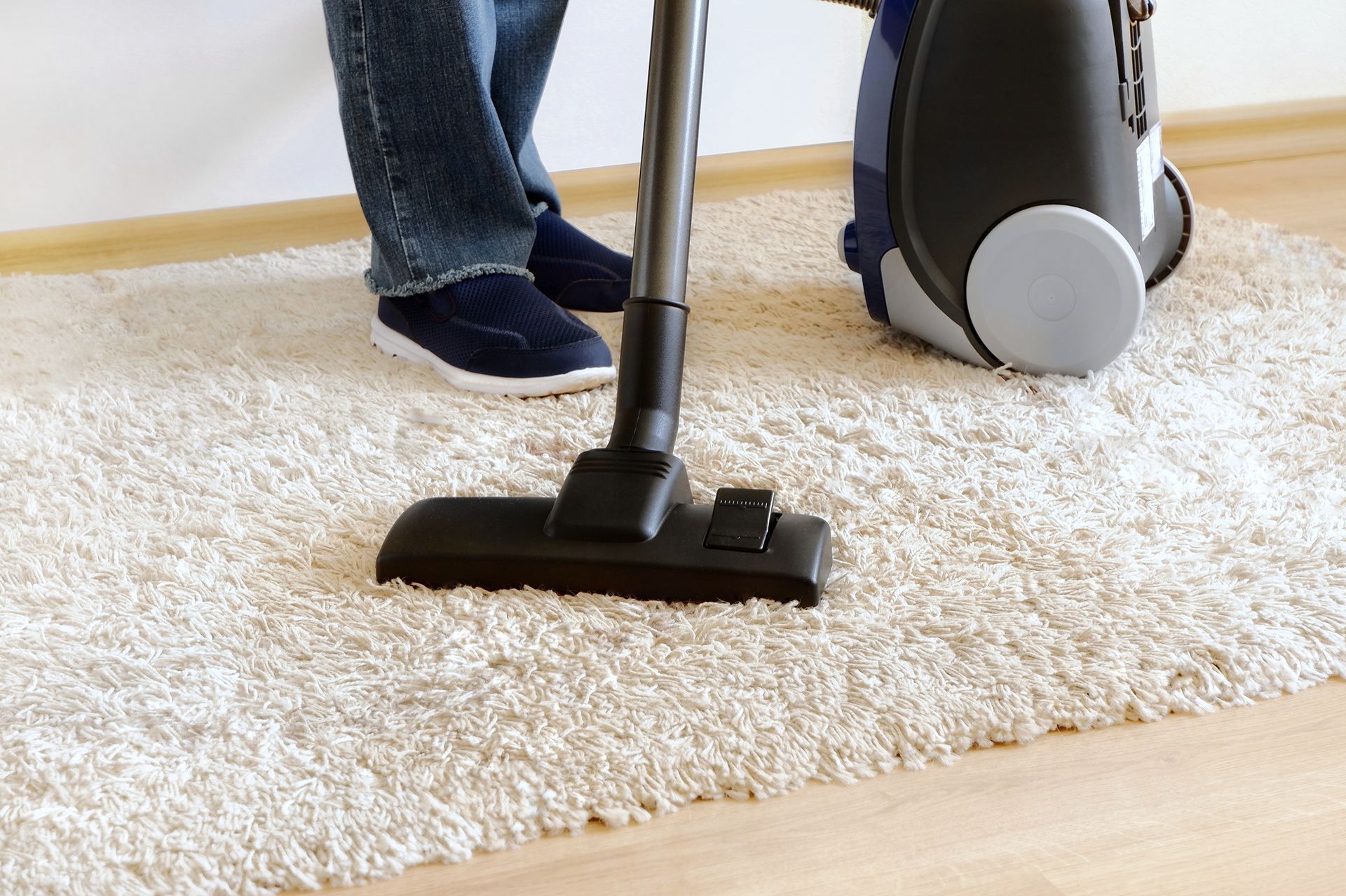 A person is using a vacuum cleaner to clean a carpet.