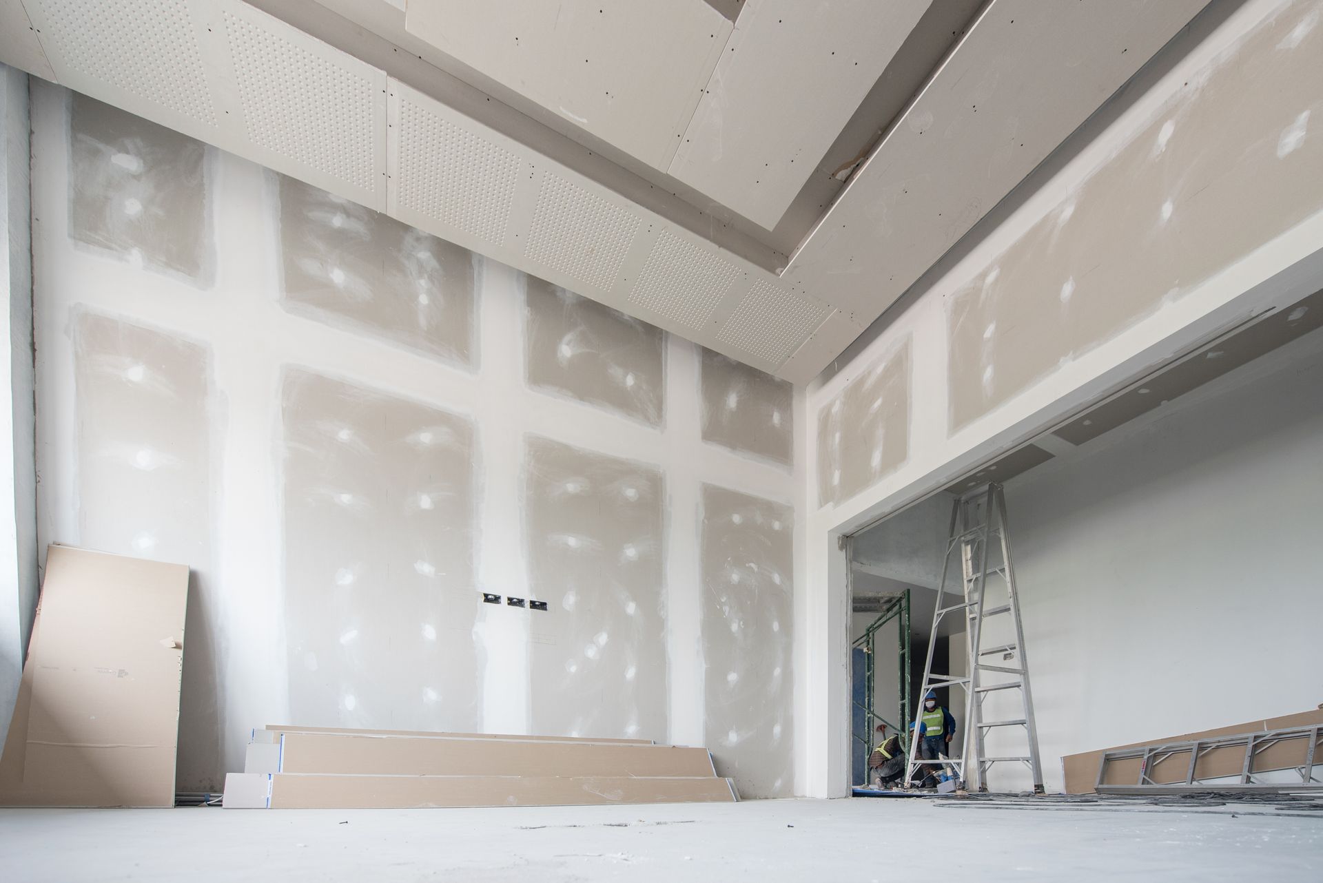 Interior under construction; drywall installation with a ladder and materials.