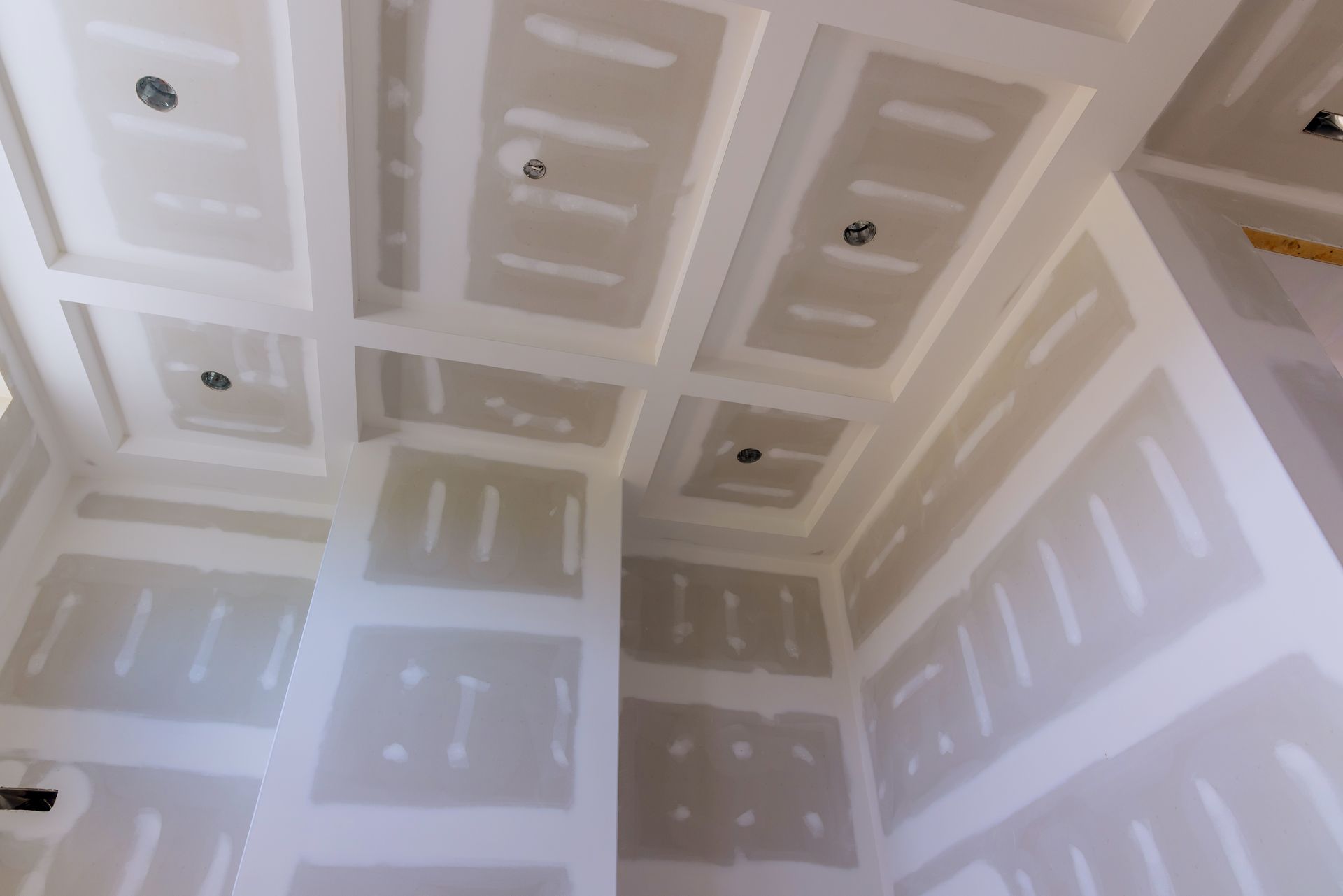 Interior walls and ceiling with rectangular recessed panels; unfinished drywall, electrical fixtures.
