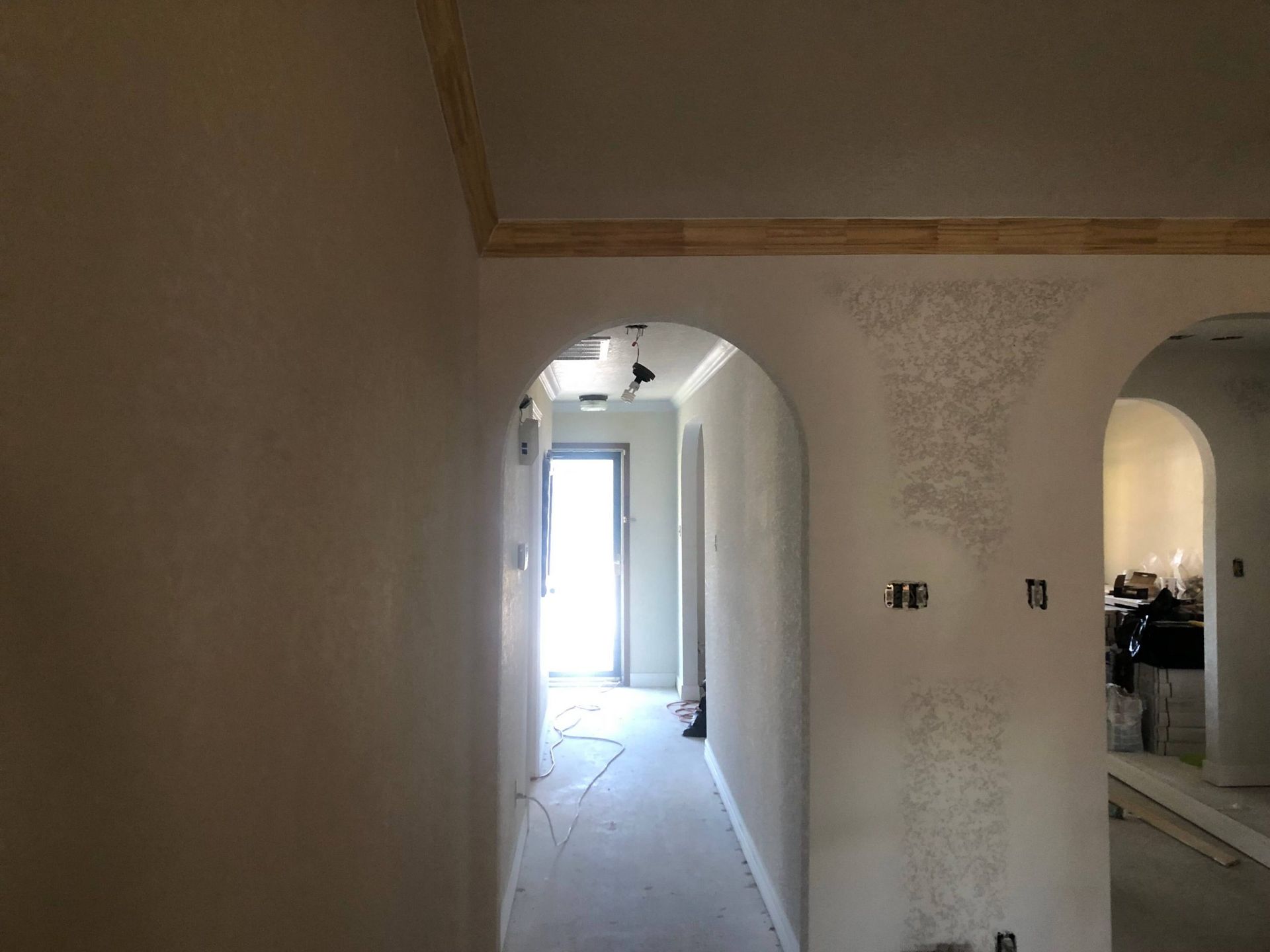 Interior hallway with arched doorways and textured walls, under construction.