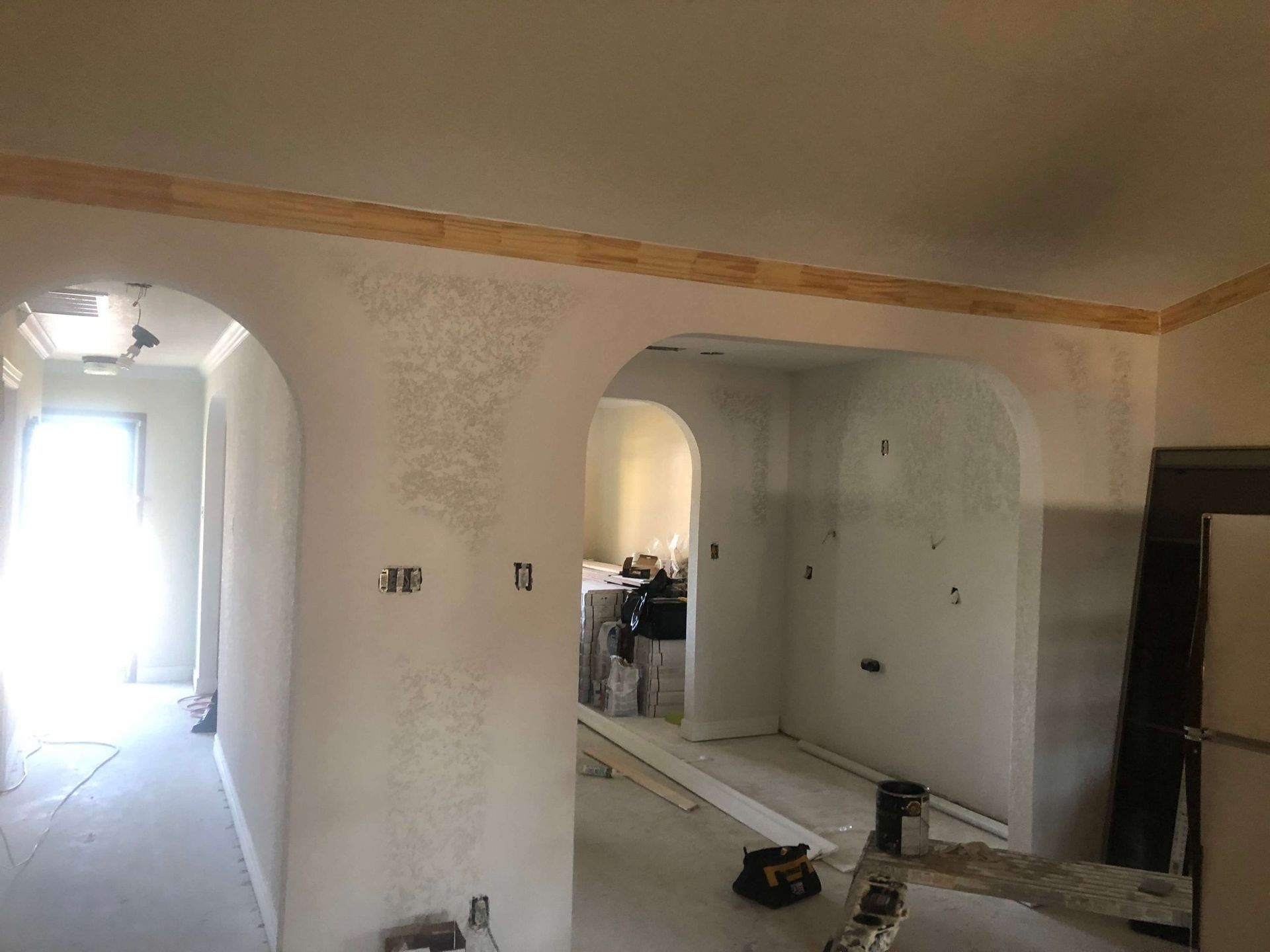 Interior renovation: Arched doorways and partially plastered walls, wood trim.