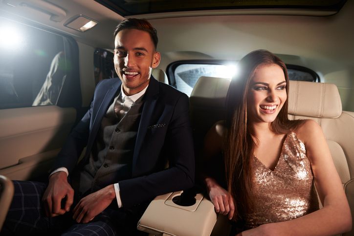 Attractive young couple laughing in the back of a limousine