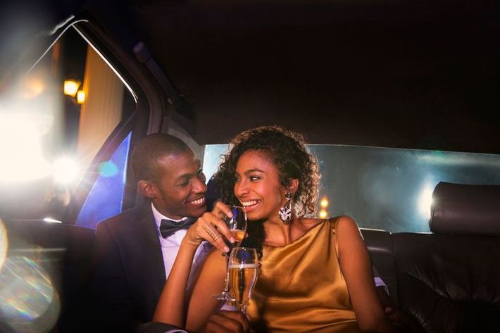 Celebrity couple drinking champagne inside limousine outside event 