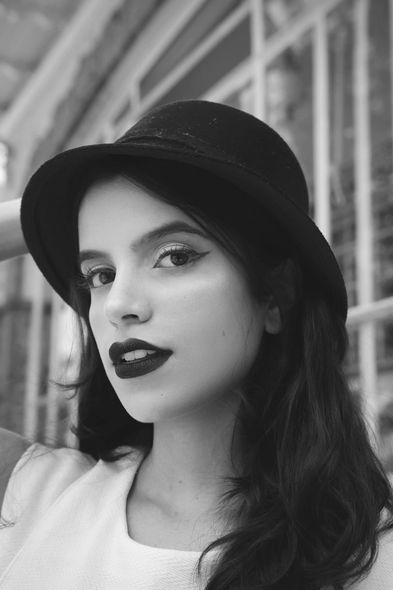 A black and white photo of a woman wearing a hat.