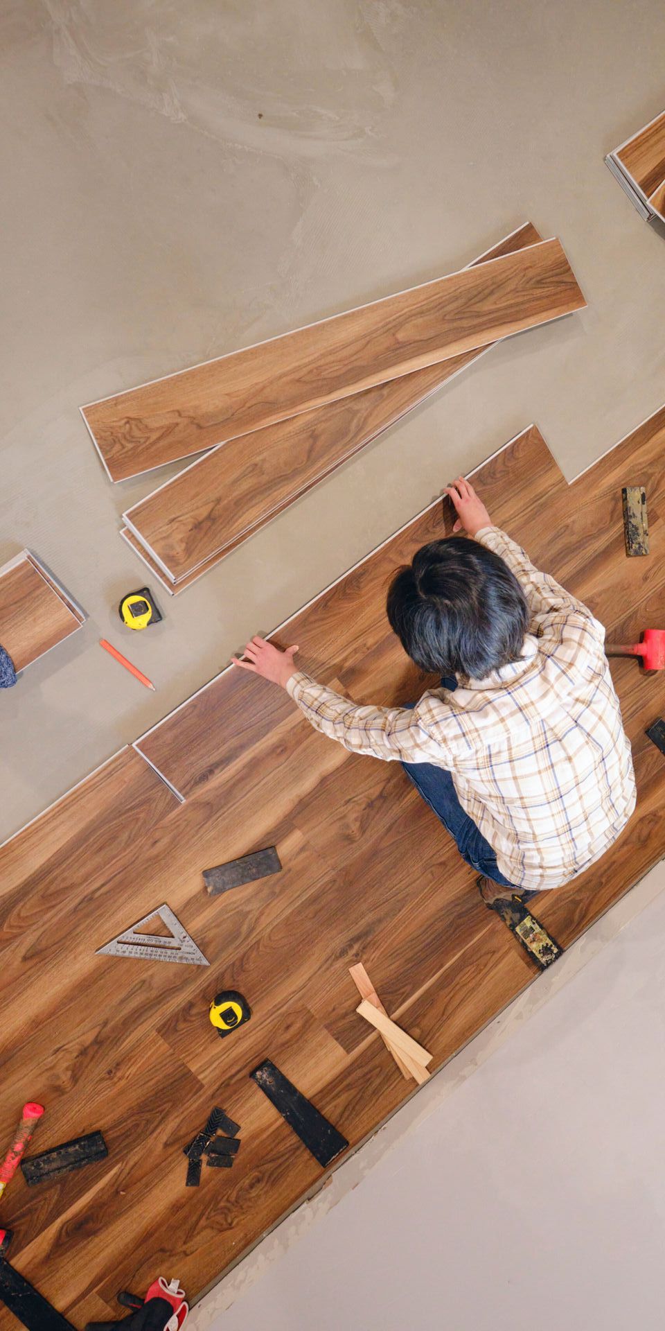 a man is sitting on the floor installing a wooden floor .