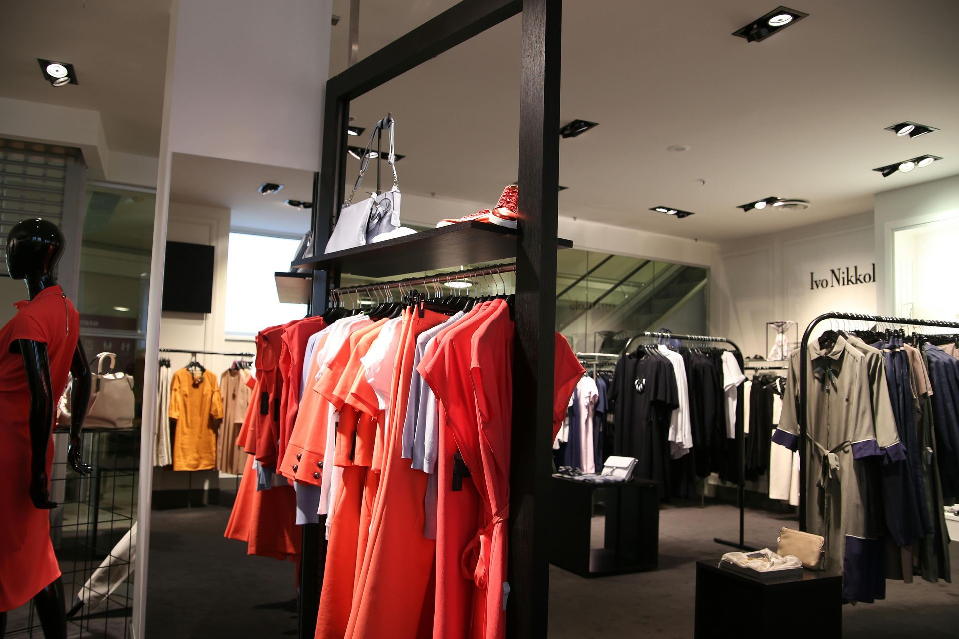 Clothing store interior with red and orange dresses on display.