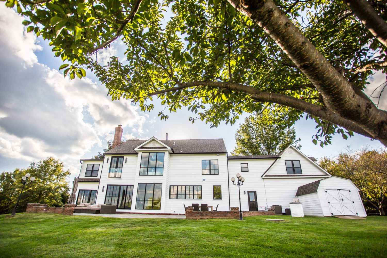 A large white house with a lot of windows is sitting on top of a lush green field.