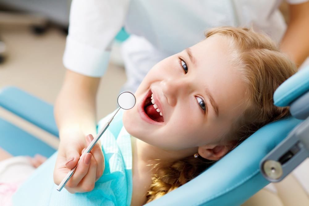 A Little Girl Is Sitting In A Dental Chair While A Dentist Examines Her Teeth — Dental Care Smithfield In Smithfield, QLD