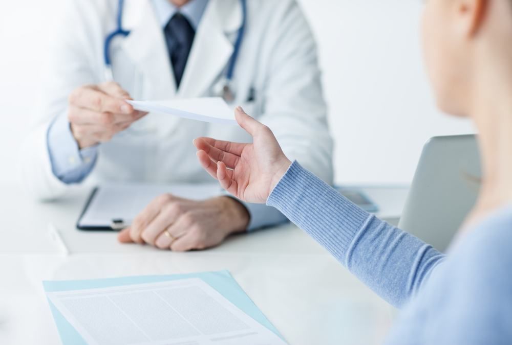 A Doctor Is Talking To A Patient While Holding A Piece Of Paper — Dental Care Smithfield In Smithfield, QLD