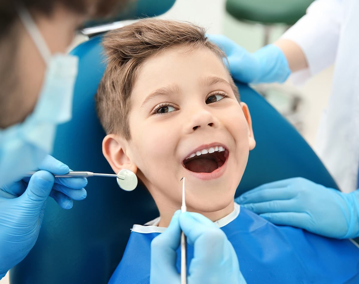 A Young Boy Is Sitting In A Dental Chair While A Dentist Examines His Teeth — Dental Care Smithfield In Smithfield, QLD